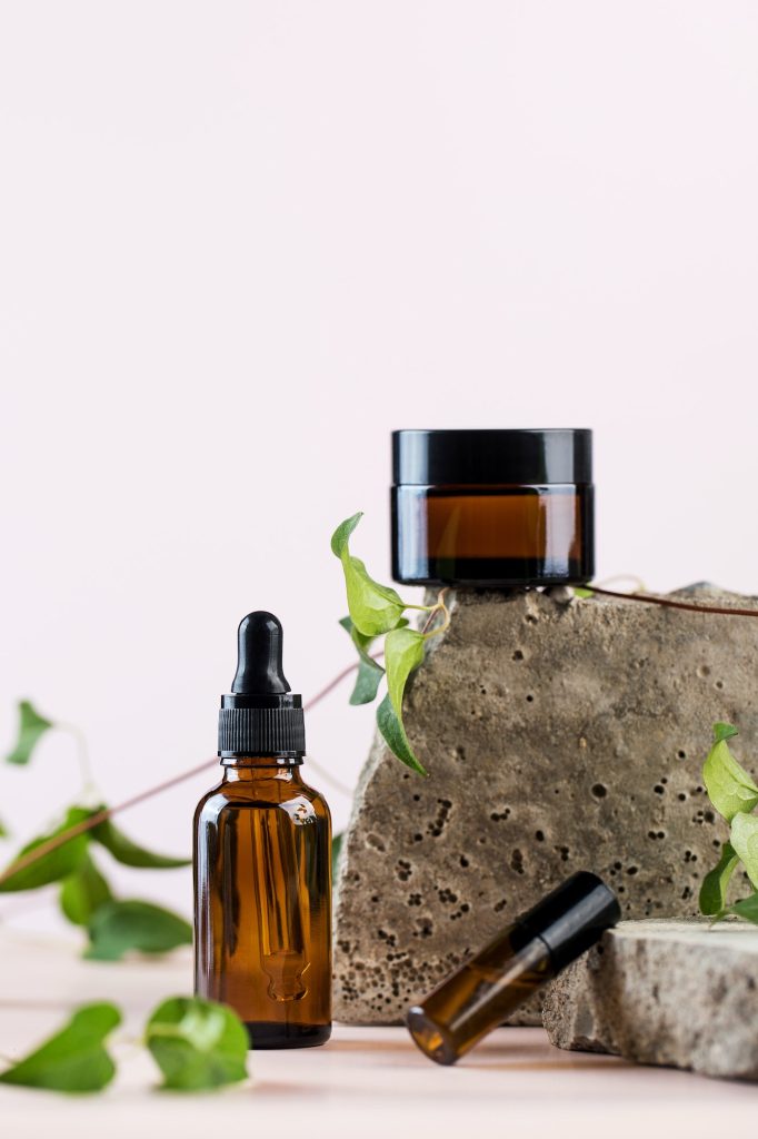 Glass bottles with organic cosmetic products on a concrete podium.